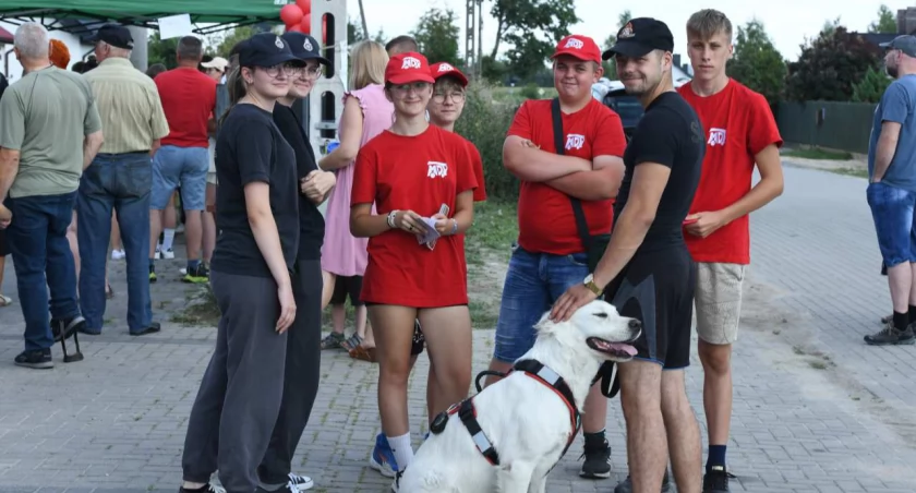 Fot. Zbigniew Woźniak   Dzień otwarty w strażnicy OSP KSRG Gręzówka. Zdjęcia ukazują zwiedzanie strażnicy, prezentację sprzętu ratowniczego, emocje dzieci i dorosłych podczas gry terenowej oraz radosne uśmiechy uczestników opuszczających wydarzenie. Atmosfera pełna zaangażowania i pozytywnych emocji, pokazująca zacieśnienie więzi między strażakami a społecznością.