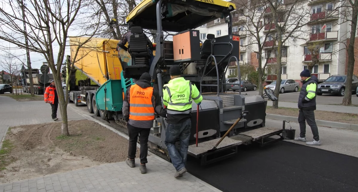 Fot. Miasto Luków. Remont w Łukowie wchodzi w finał. Na ul. Partyzantów, od świateł przy Wyszyńskiego, drogowcy wylewają nową masę bitumiczną. Wcześniej wymieniono krawężniki, poprawiono zjazdy i ułożono chodniki. Prace odbywają się pod ruchem, dlatego kierowcy muszą liczyć się z wolniejszą jazdą i ręcznym kierowaniem ruchem. Jeśli pogoda dopisze, wkrótce będzie równo i bez dziur.